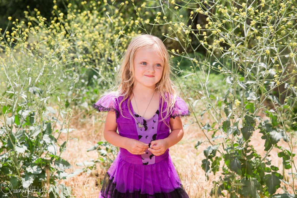 A purple dress contrasts beautifully with the natural greenery and golden light in an outdoor garden setting.