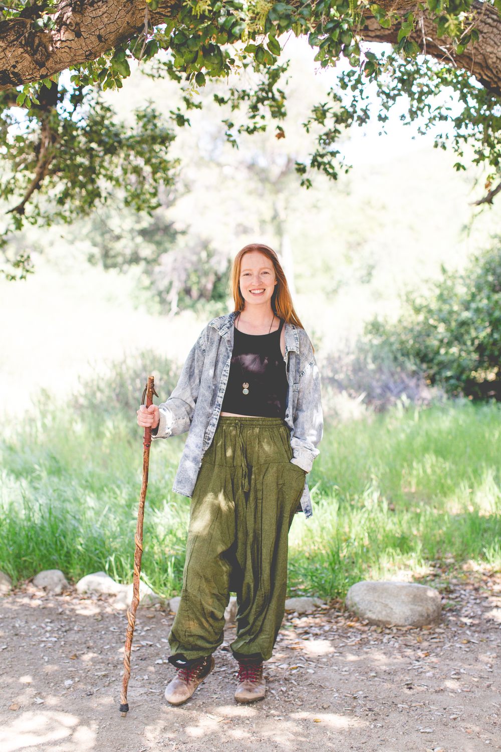 Four sequential photos showing someone wearing olive green overalls and a gray cardigan holding a walking stick outdoors.