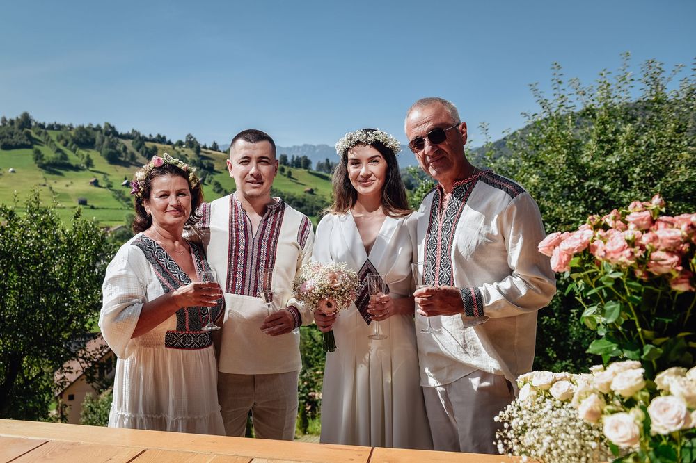 A group of people in white outfits enjoying wine and snacks during an outdoor summer gathering in a scenic vineyard setting.
