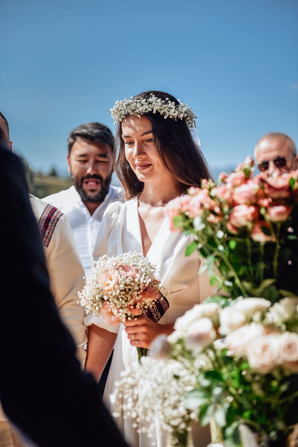 A close-up view of a wedding party with pink roses and baby's breath floral arrangements in the foreground.