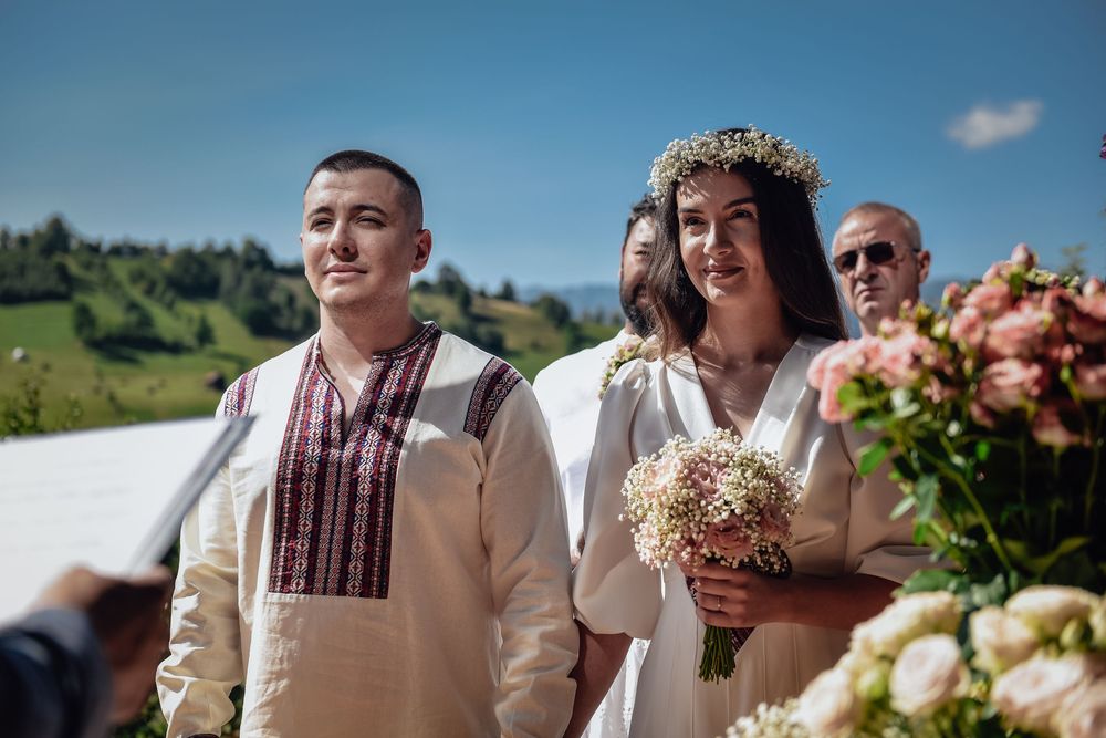 Outdoor wedding celebration with guests gathered in a scenic mountain landscape on a sunny day.