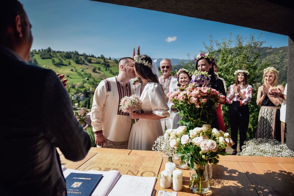 Wedding ceremony setup with rustic wooden decor against a backdrop of rolling green hills and blue sky.