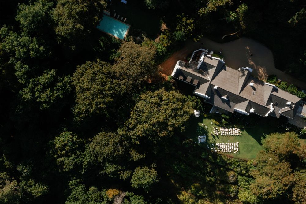 Aerial view of houses and properties surrounded by lush green trees.