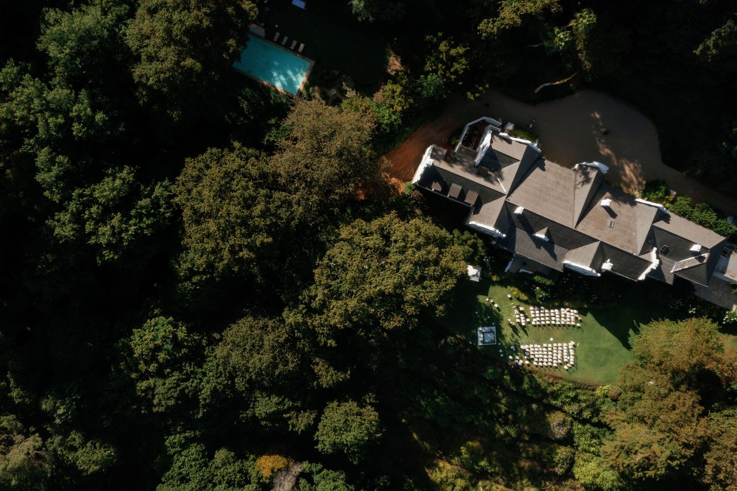 Aerial view of houses and properties surrounded by lush green trees.