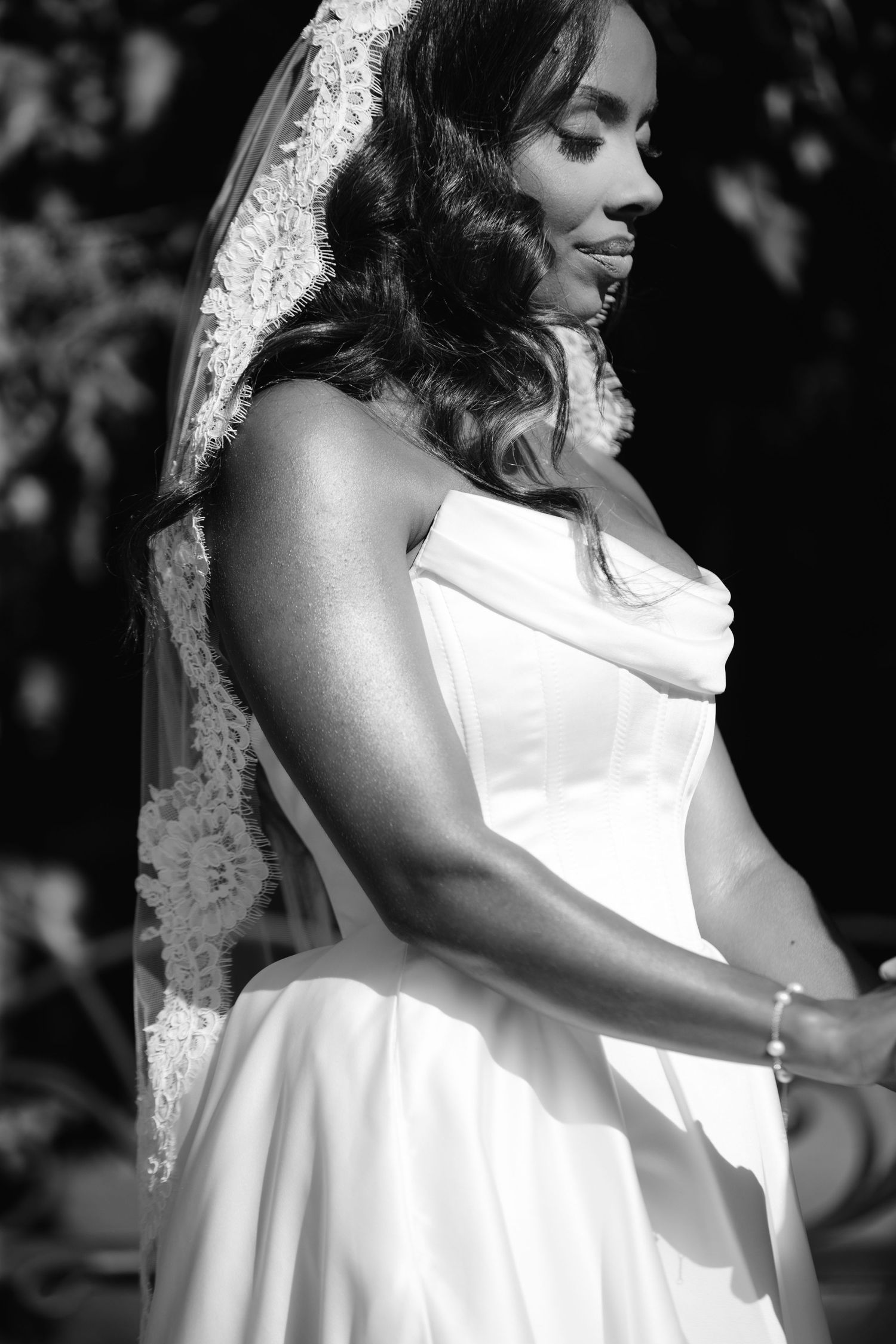 Black and white portrait of a bride in a sleeveless white dress with a delicate veil.