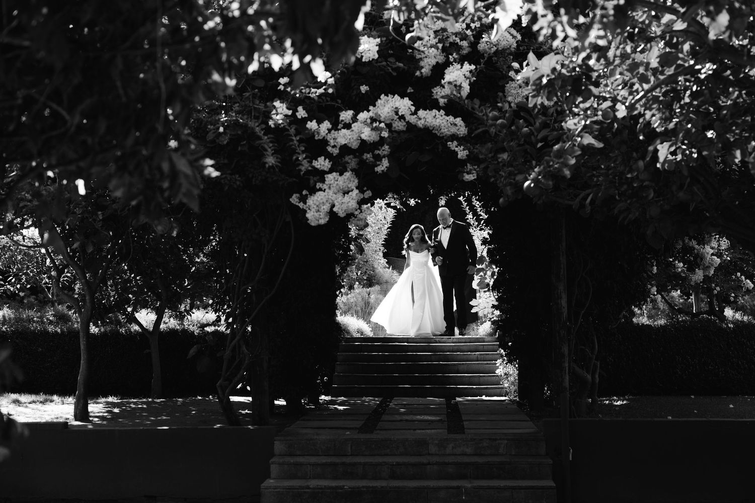 A couple shares a romantic moment on their wedding day in a serene garden setting with lush greenery.