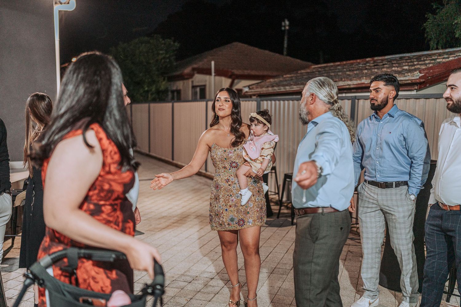 Wedding guests mingling and dancing outdoors during an evening celebration.