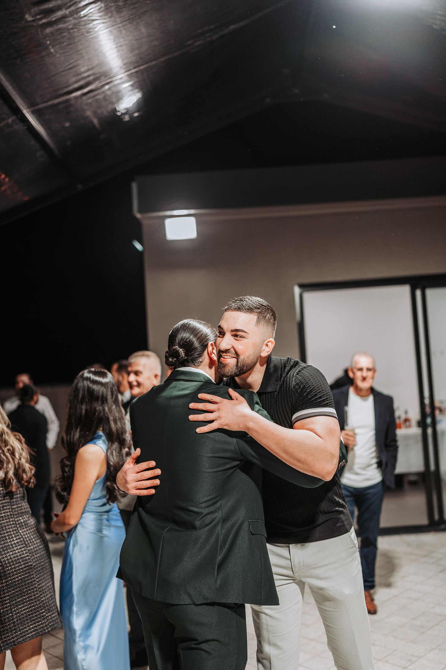 Emotional embrace shared between guests at an indoor celebration event.