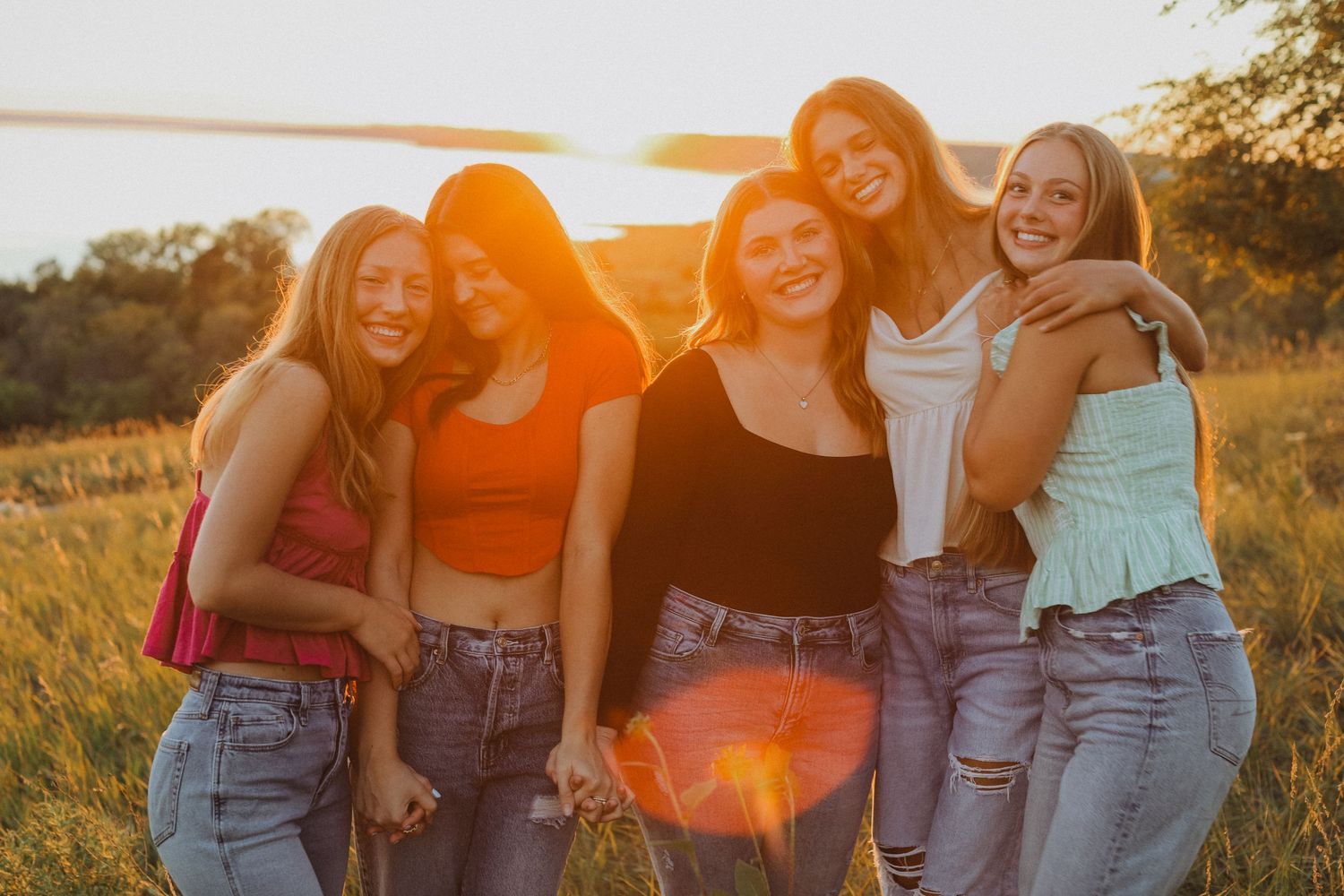 Friends in casual denim outfits laughing together at sunset.