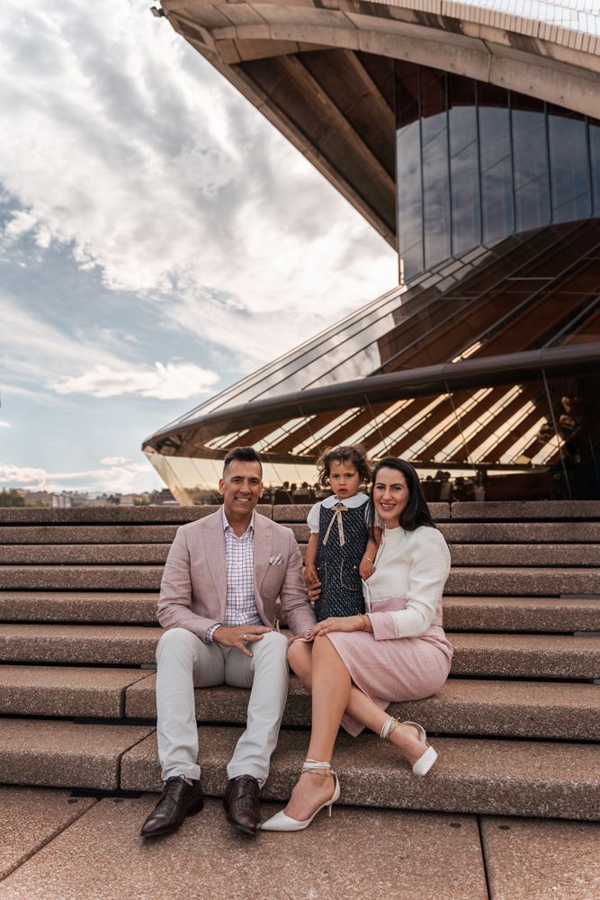 Family sitting on the Sydney Opera House stairs during a family photoshoot, capturing the city’s architectural