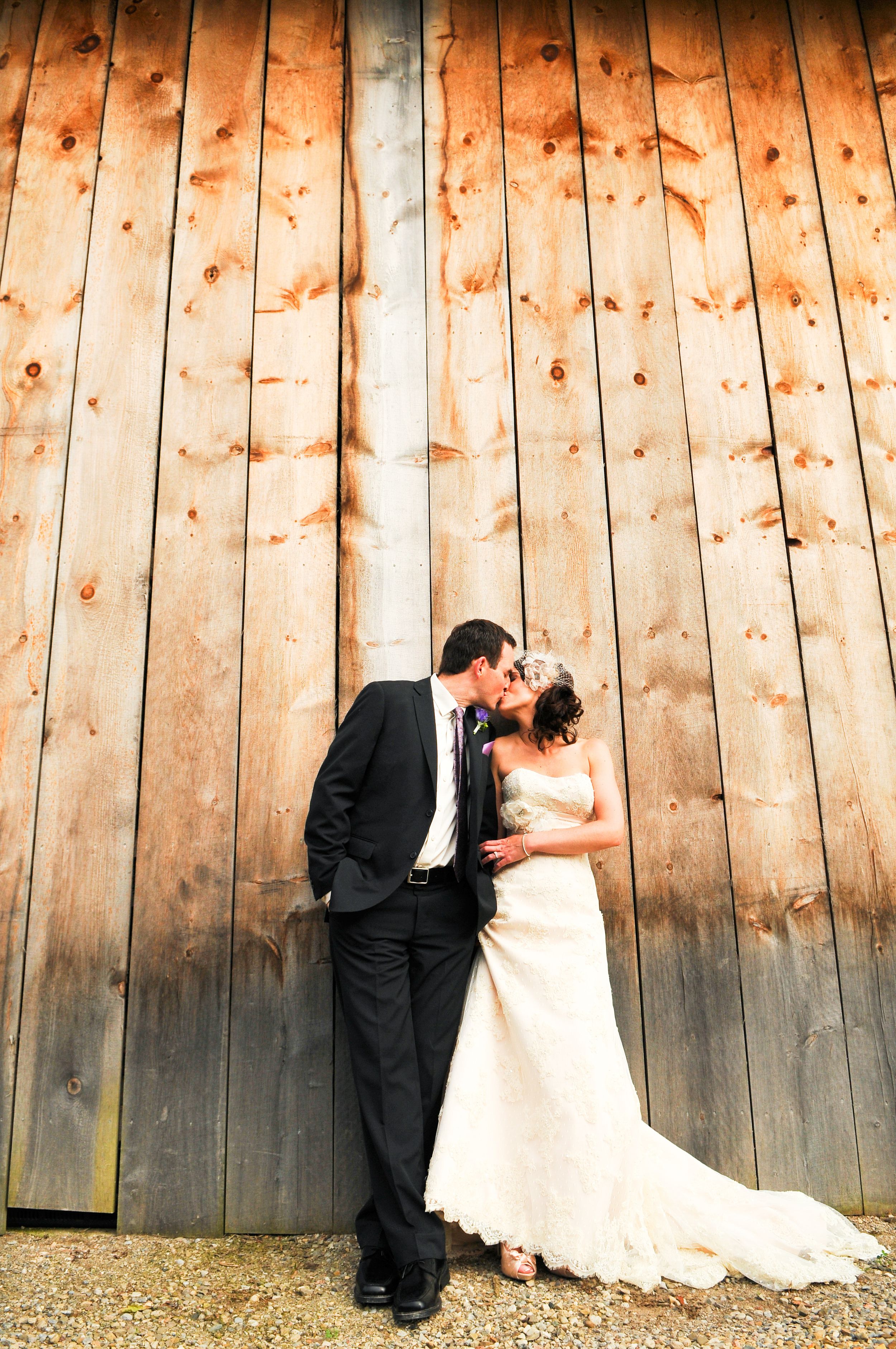 A romantic wedding photo against rustic wooden barn walls.