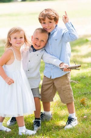Three young children playing outdoors in casual summer clothing.