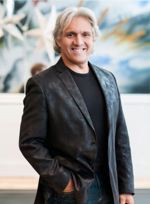 A casual business portrait of someone in a black blazer against a blurred background.