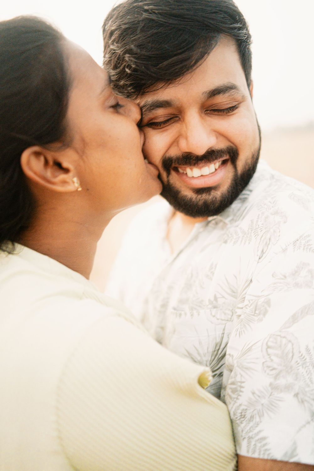 A sweet moment shared between a couple during a beach photoshoot.