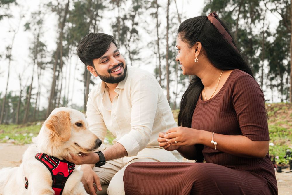 A couple sits outdoors with their Golden Retriever, sharing a tender moment together.