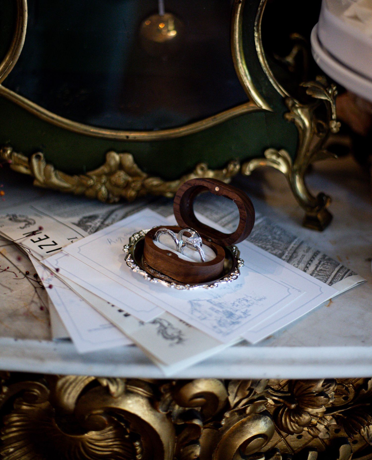 Detail shot of wedding rings and invitation front of an antique clock.