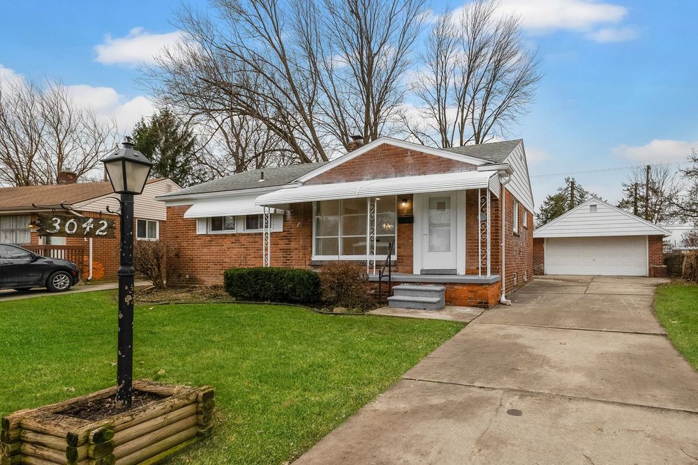 Brick ranch home at 3042 with green lawn, covered porch, attached garage, and mature trees on a clear day.