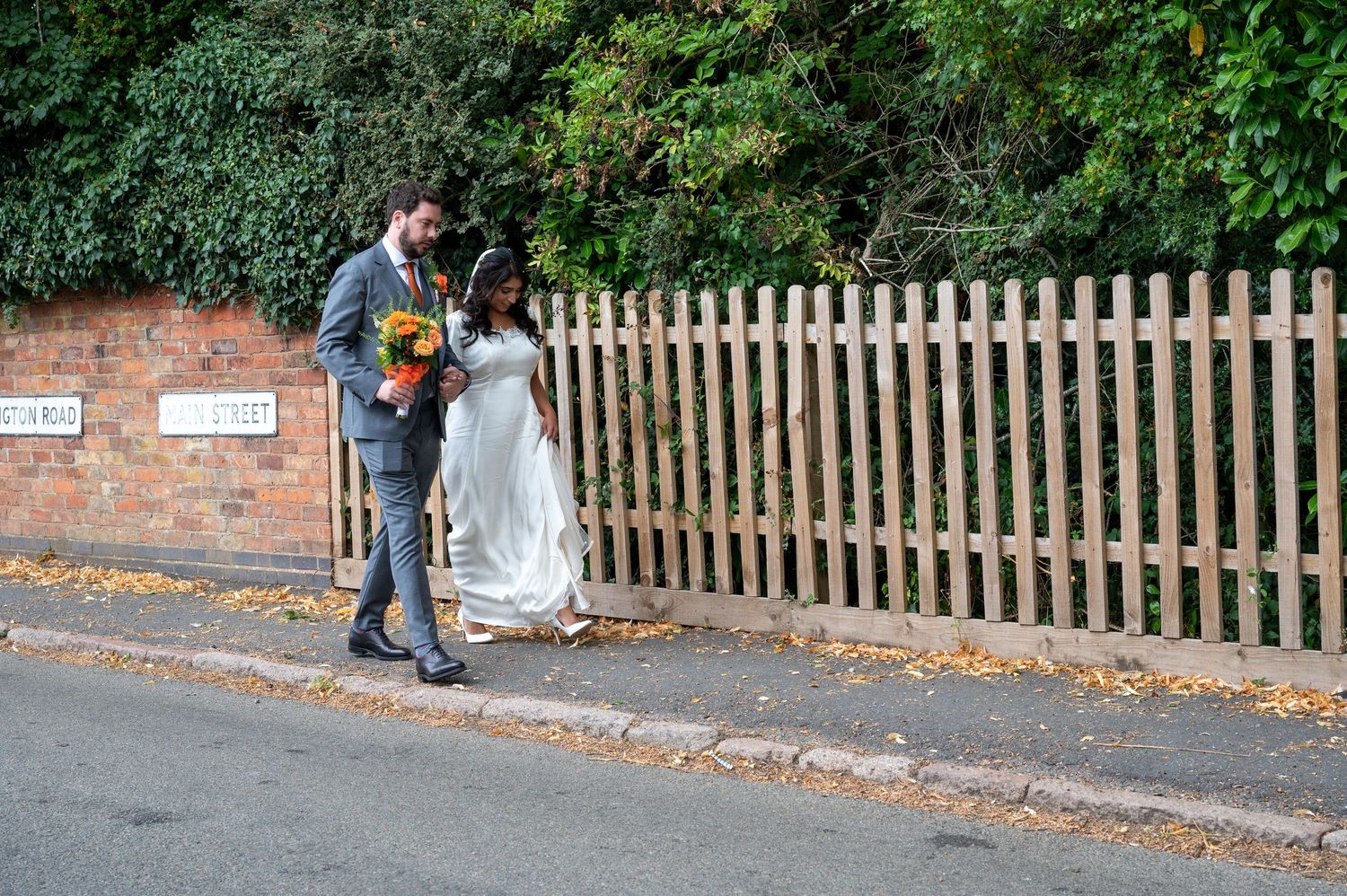 Couple walking down the street from the church to their reception during weekday wedding