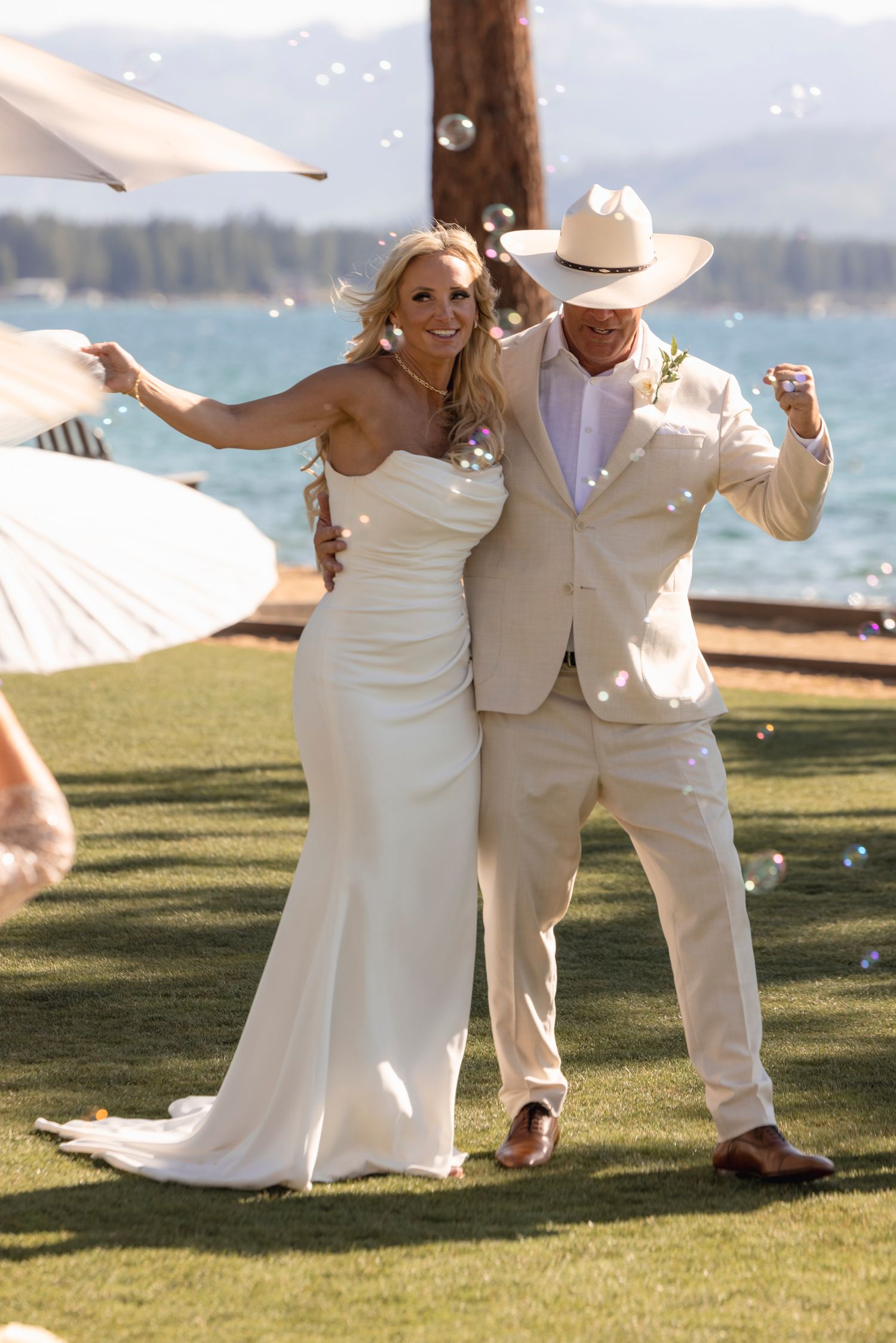 A bride and groom share an intimate moment outdoors, she holds a lush red and white bouquet while wearing a lace gown.