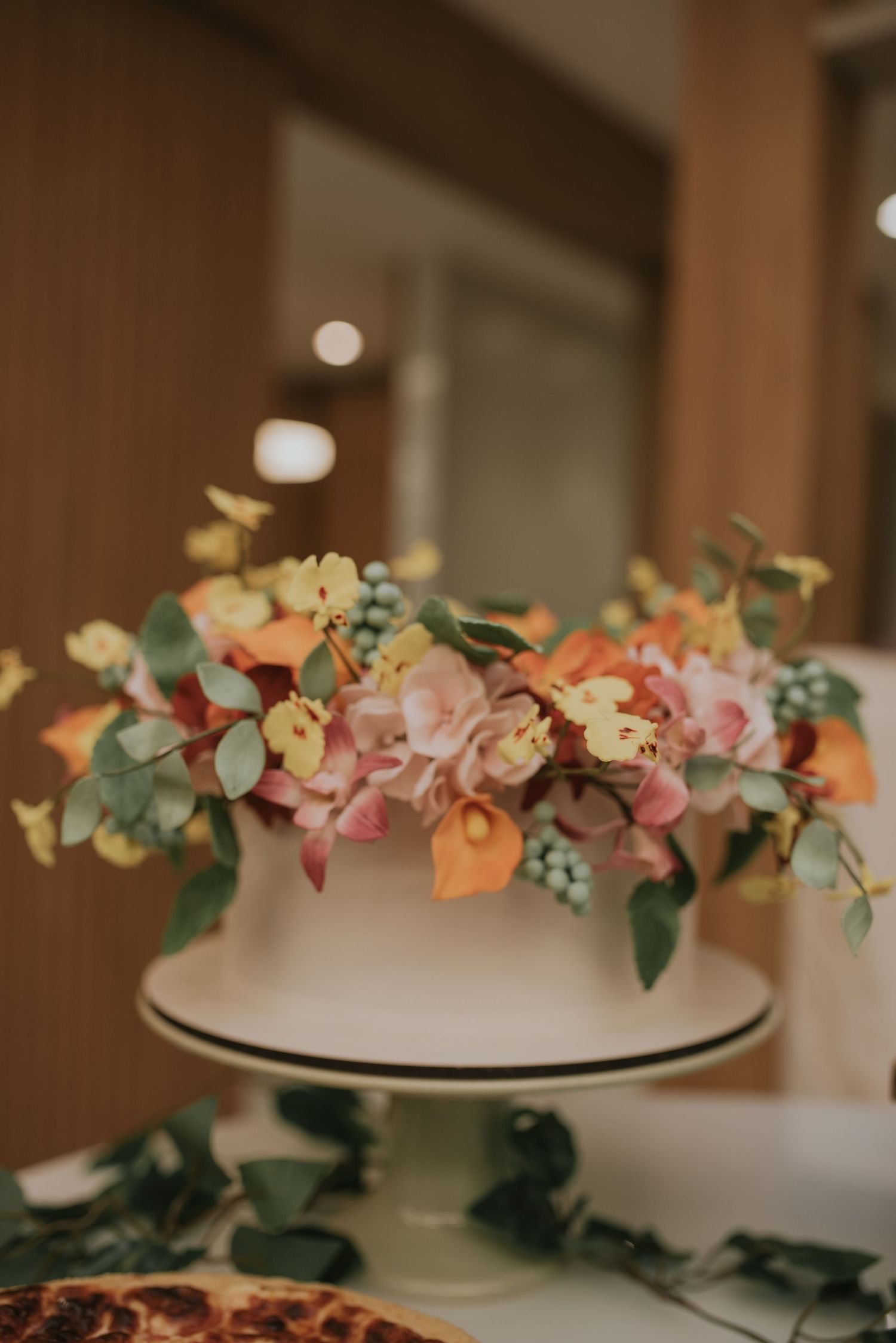 Wedding cake decorated with delicate pink and peach flowers with eucalyptus leaves.