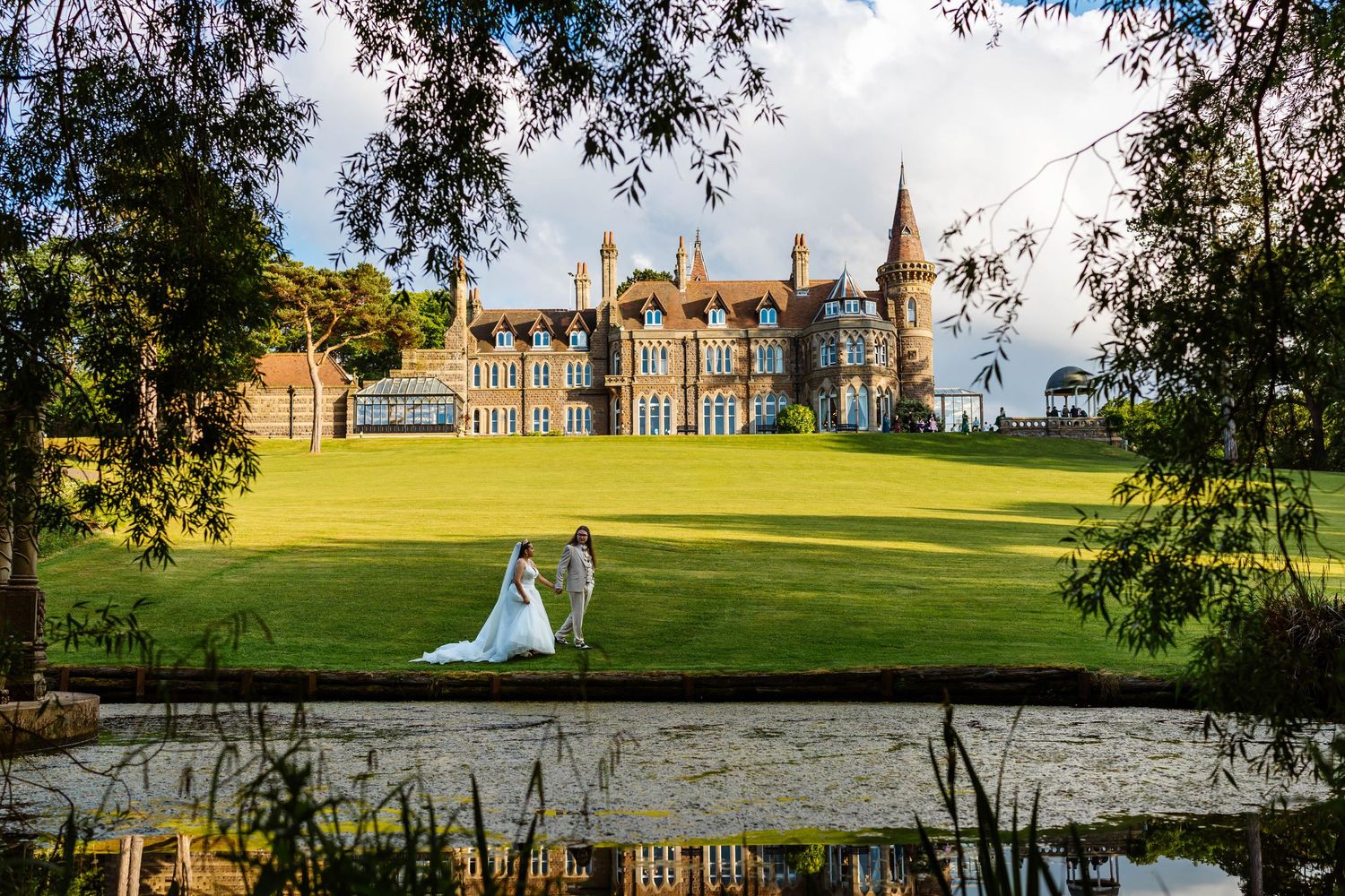 Bride and groom walking on lush green lawn before a grand historic manor house wedding venue at Rushpool Hall, Middlesborough