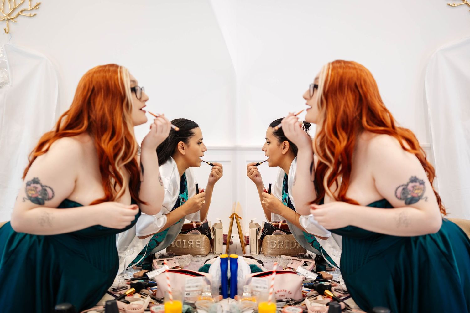 Bride and her maid of honour applying lipstick in the mirror - candid shot captured by Lynette Matthews Photography