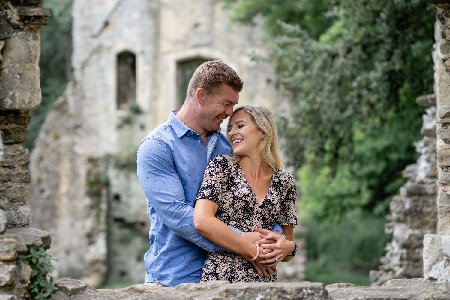 Couple sharing a romantic kiss in a lush green meadow field on a cloudy day.
