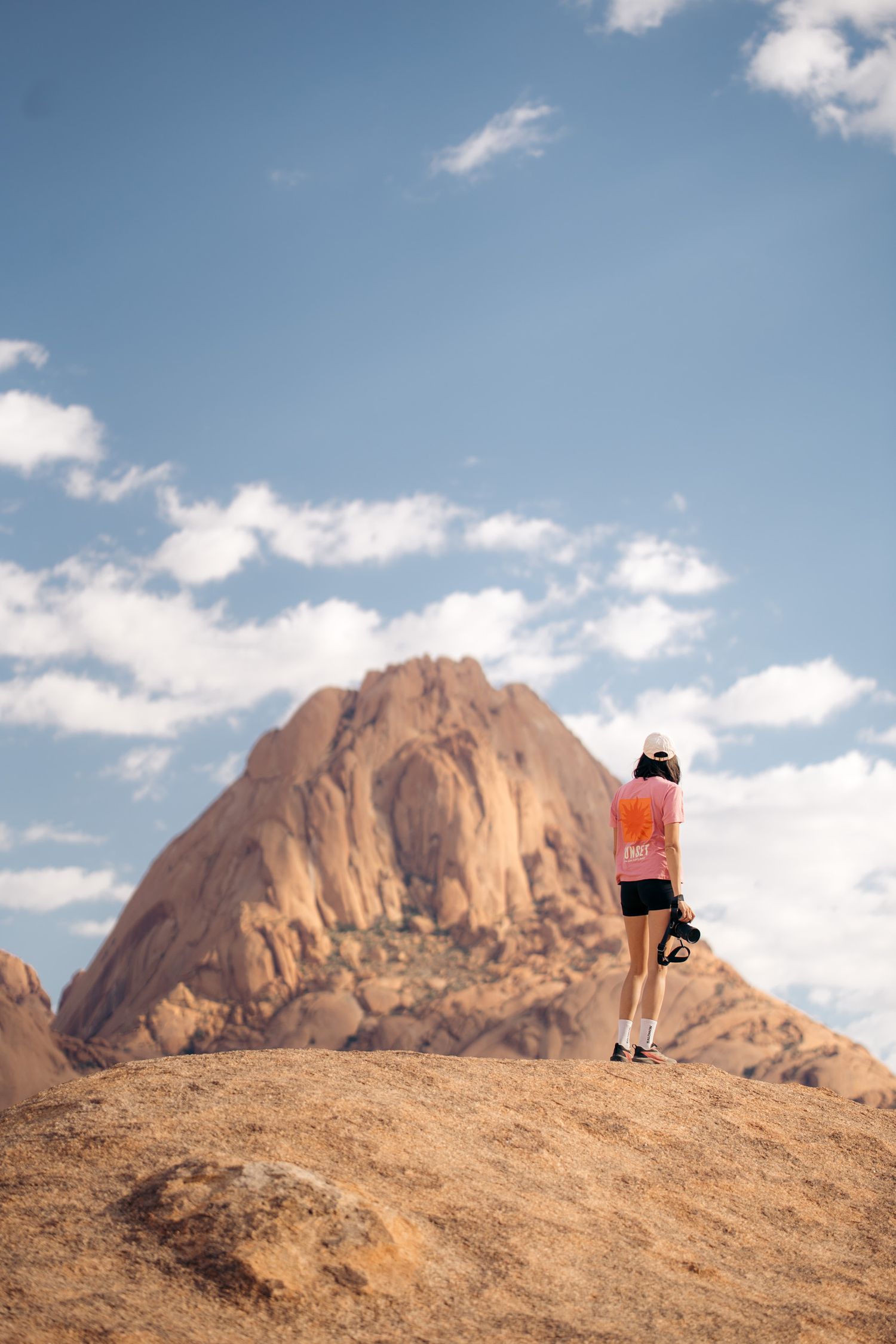 photographe de dos avec le smontagnes de spitzkoppe en arrière-plan