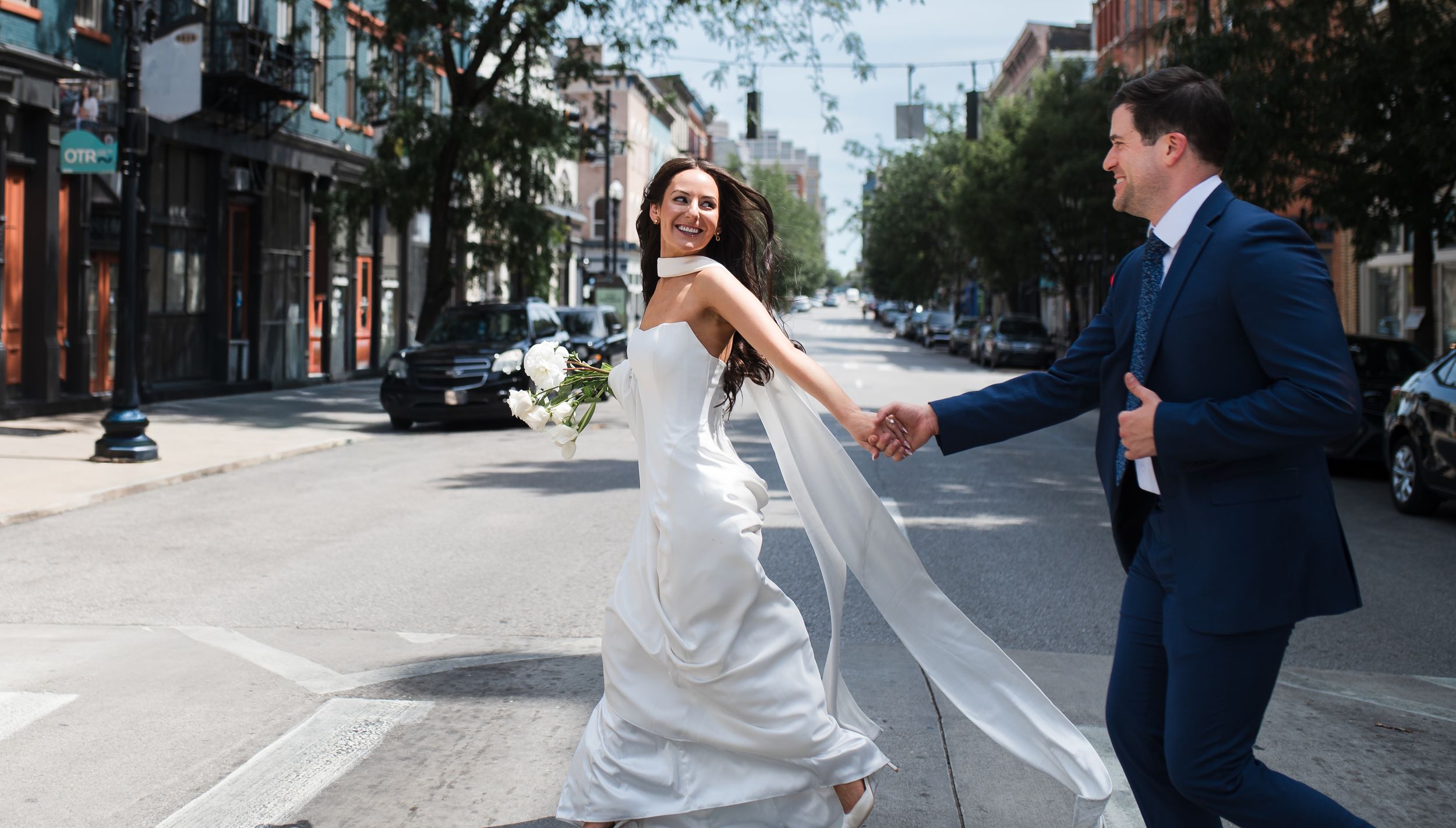 Bride and groom walk down the aisle at an outdoor wedding ceremony with bridesmaids in navy dresses.