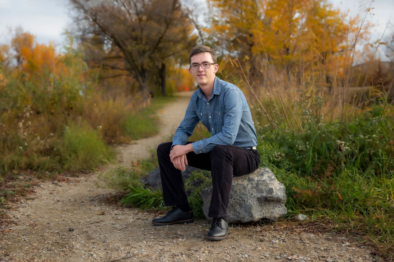 Senior boy sitting on rock in Autumn