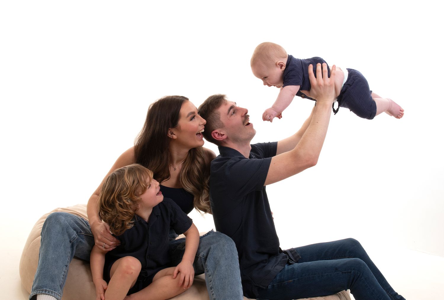 Four happy children laughing and posing together on a white background, two teenage girls, a young girl, and a boy.