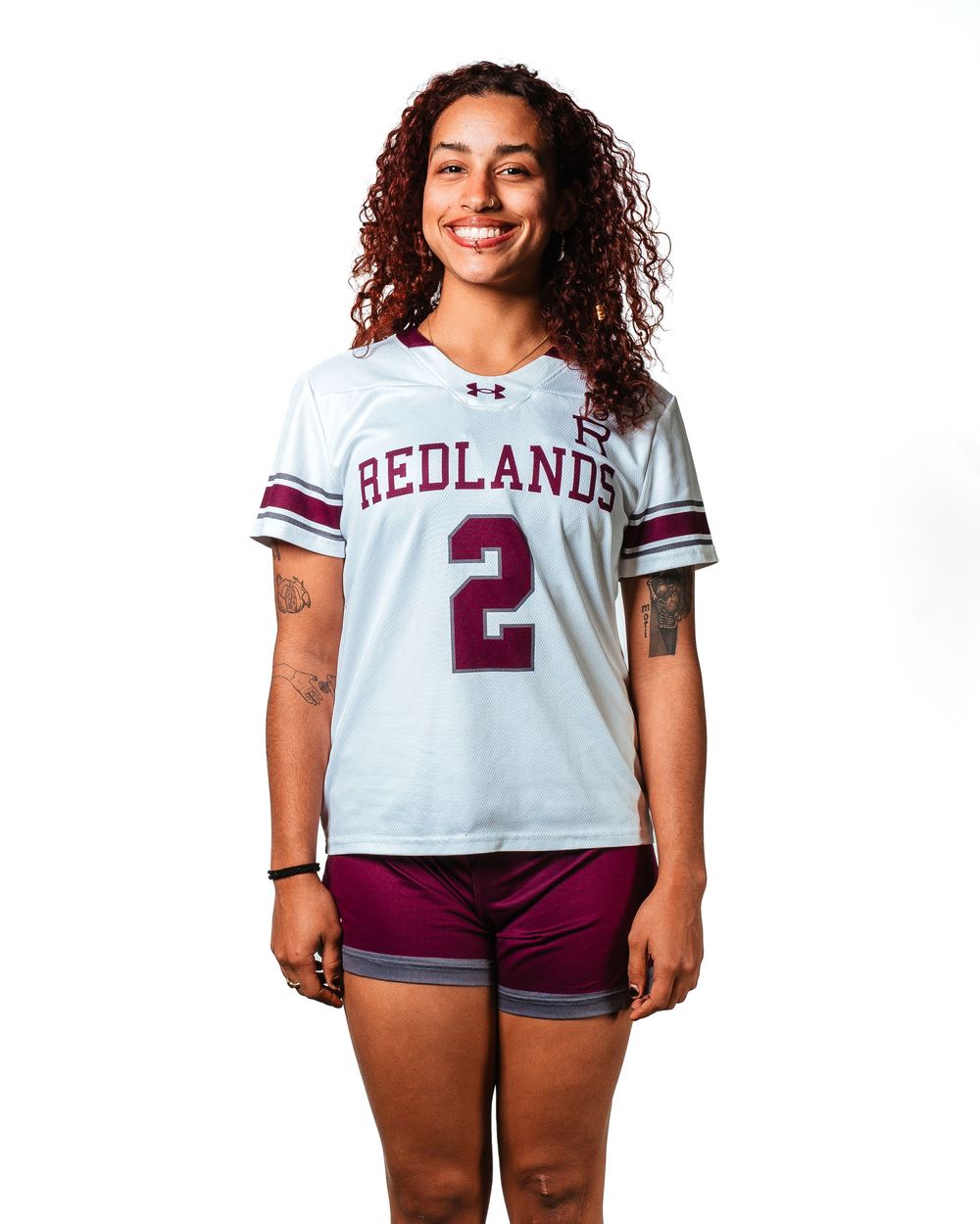 Redlands University athlete wearing white number 2 jersey and maroon shorts poses for official team photo.