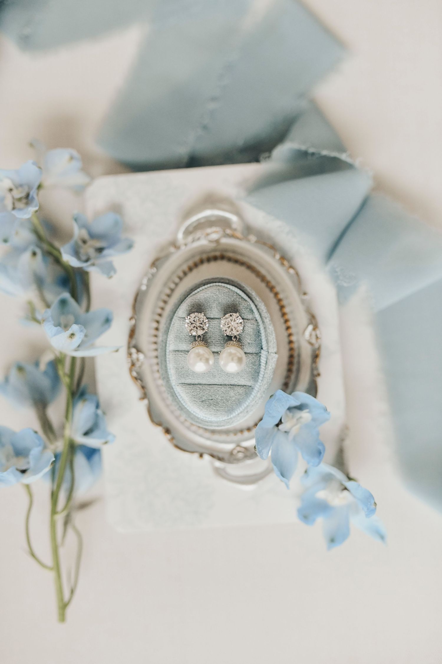 Bridal accessories photographed with fresh delphinium flowers