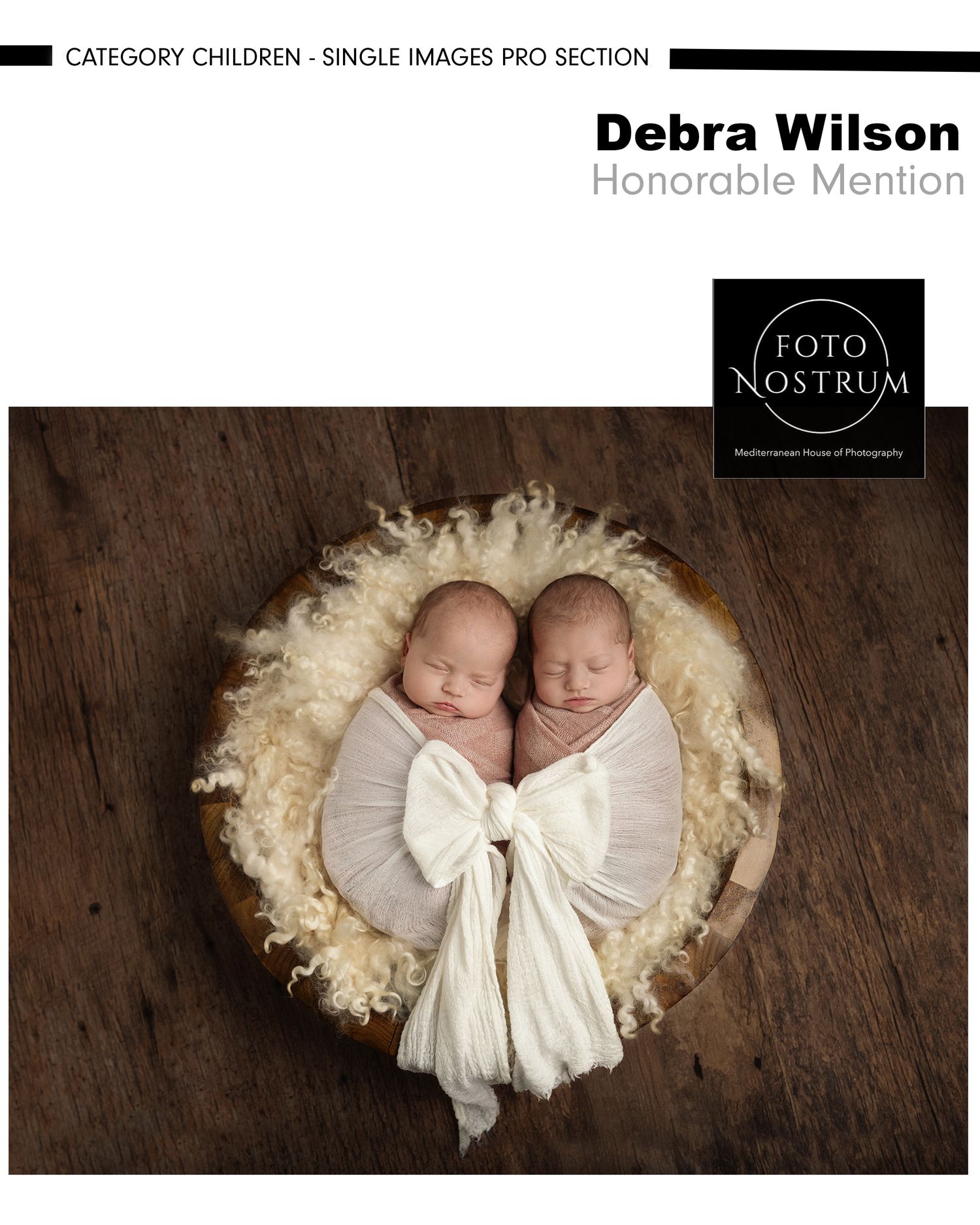 Two sleeping newborn twins wrapped in white swaddles rest together in a wooden bowl lined with fluffy fur.