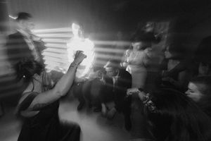 Black and white photo of a crowded dance floor with motion blur at a lively party.