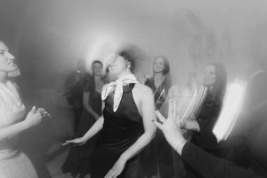 Black and white photo of people dancing joyfully at a lively party or wedding reception event.