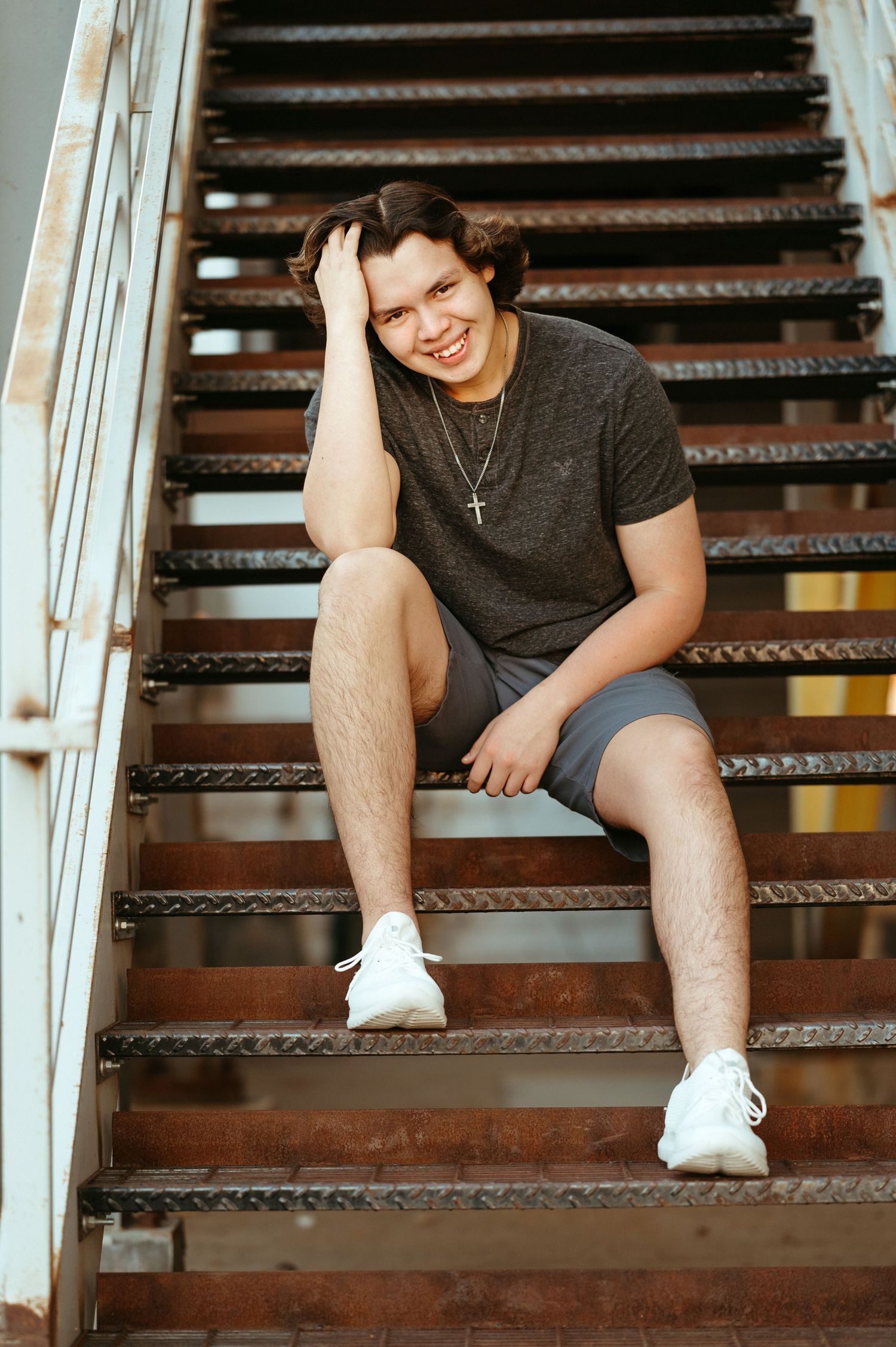 Senior boy photographed on rustic stairs with clean masculine posing, natural expression and modern Brookings SD senior portrait styling.