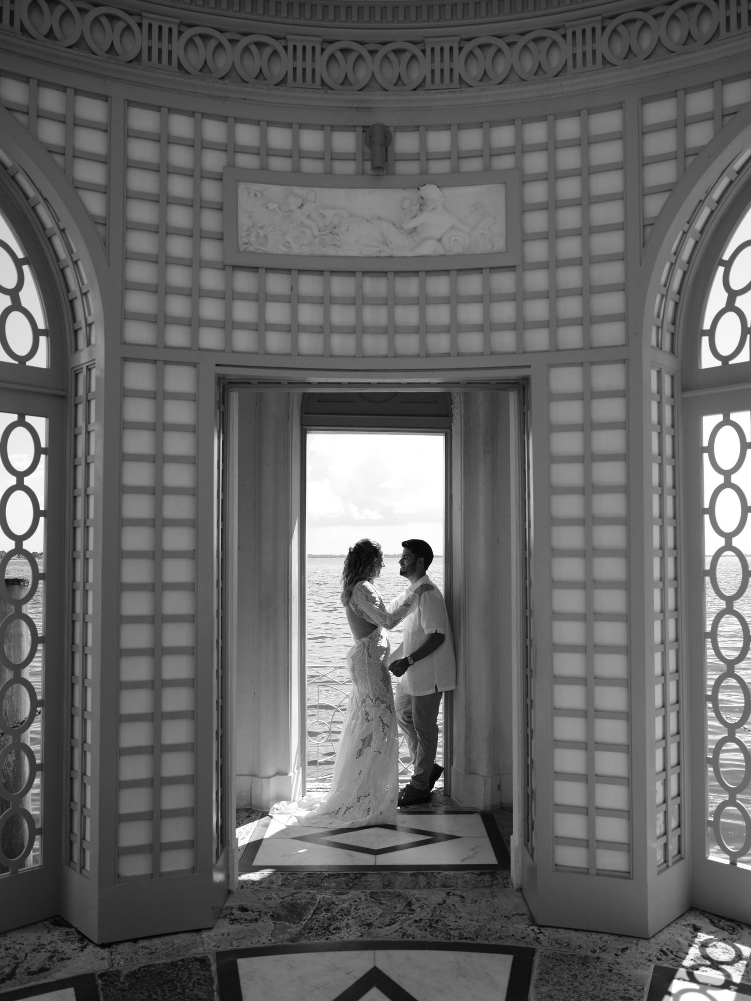 Bride and groom share an intimate moment inside Vizcaya’s waterfront pavilion, framed by elegant architecture and bay views.