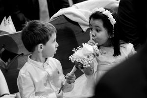 Two young children in formal attire share a candid moment during a wedding celebration.