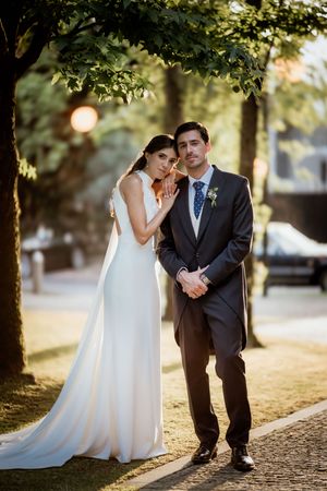 A tender moment between newlyweds posing under a tree during golden hour.