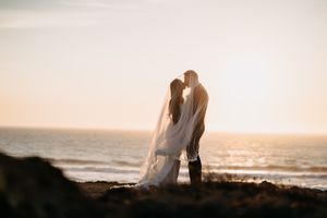 Silhouetted couple embraces against a golden sunset at the beach.