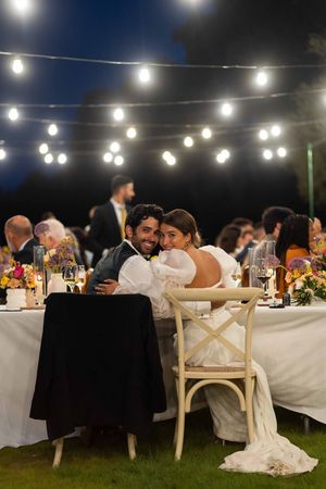 Outdoor wedding reception under twinkling string lights with long tables and white decor.