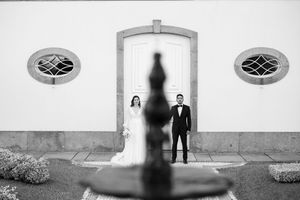 Minimalist black and white wedding portraits against white wall with architectural elements.