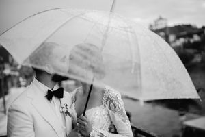 Black and white intimate moment of couple sharing umbrella during wedding portraits.