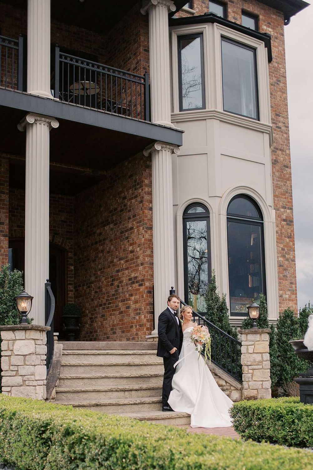Bride and groom pose in front of the Estate Washington Wedding open house Manor House