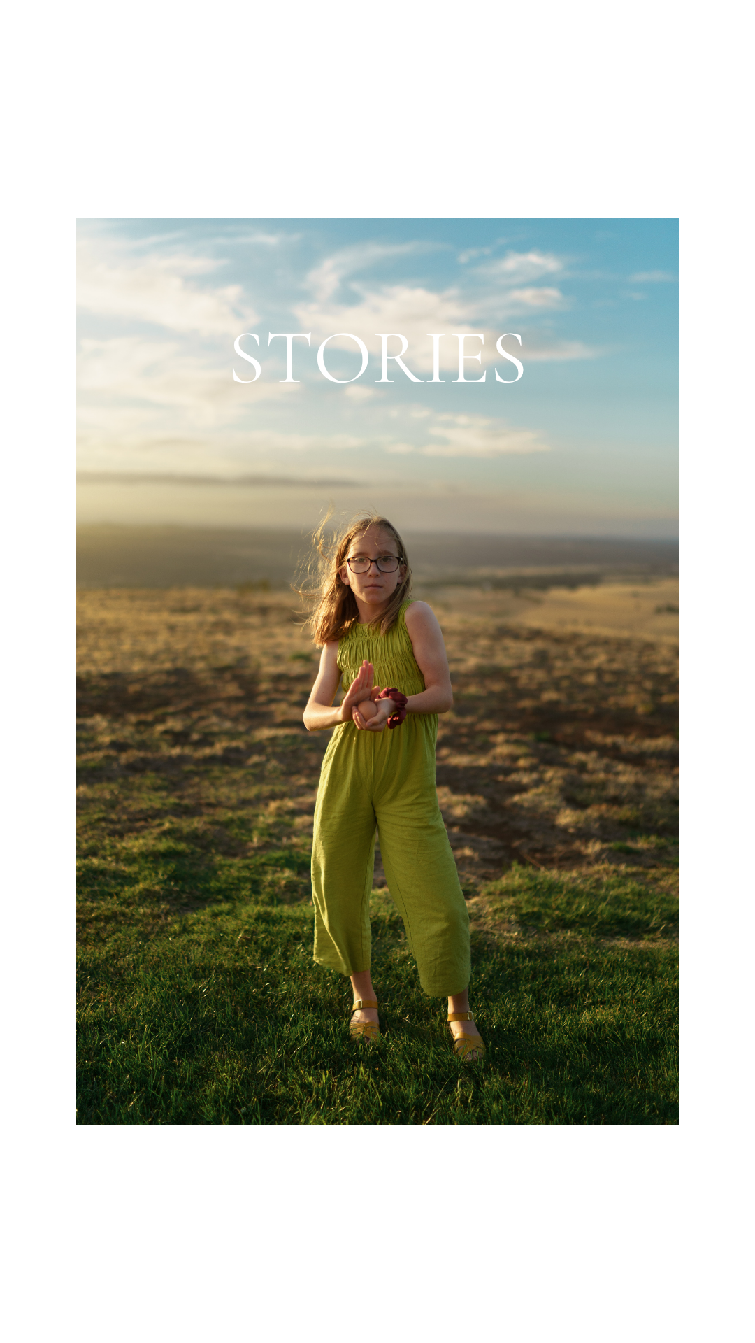 Young woman in green jumpsuit standing in an open field at sunset with the word STORIES overlaid.