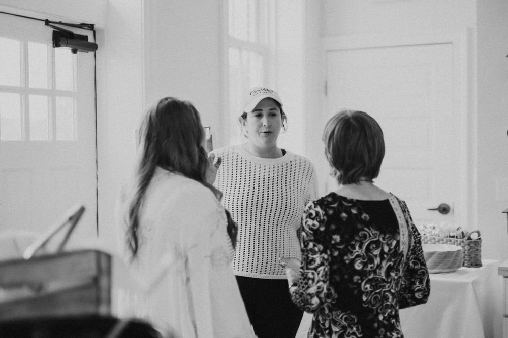 Three women conversing in a bright, airy room in a candid black and white photo.