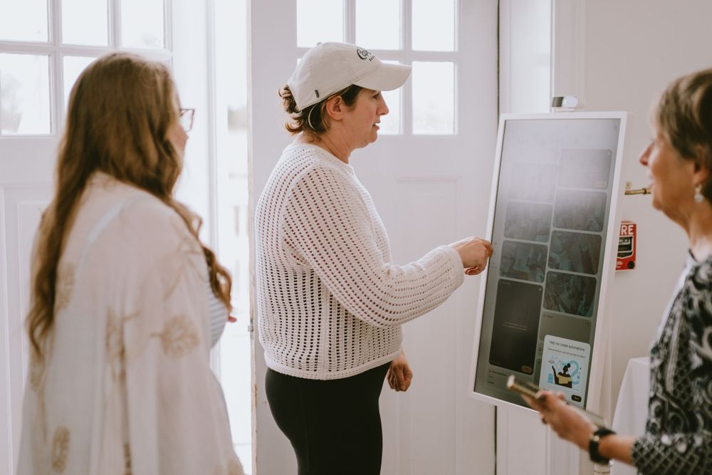 Two women reviewing tile samples on a display board in a bright interior design consultation setting.