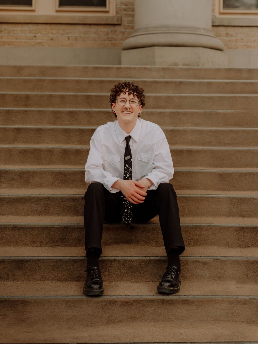 Boy sits on stairs and poses for graduation photos at CSU (Colorado State University) graduation photos in Fort Collins, Colorado