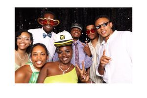 Group of seven friends posing together at a formal event, wearing festive accessories and elegant attire at a photo booth.